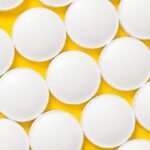 White round pills on a vibrant yellow background showcasing a pharmaceutical theme.